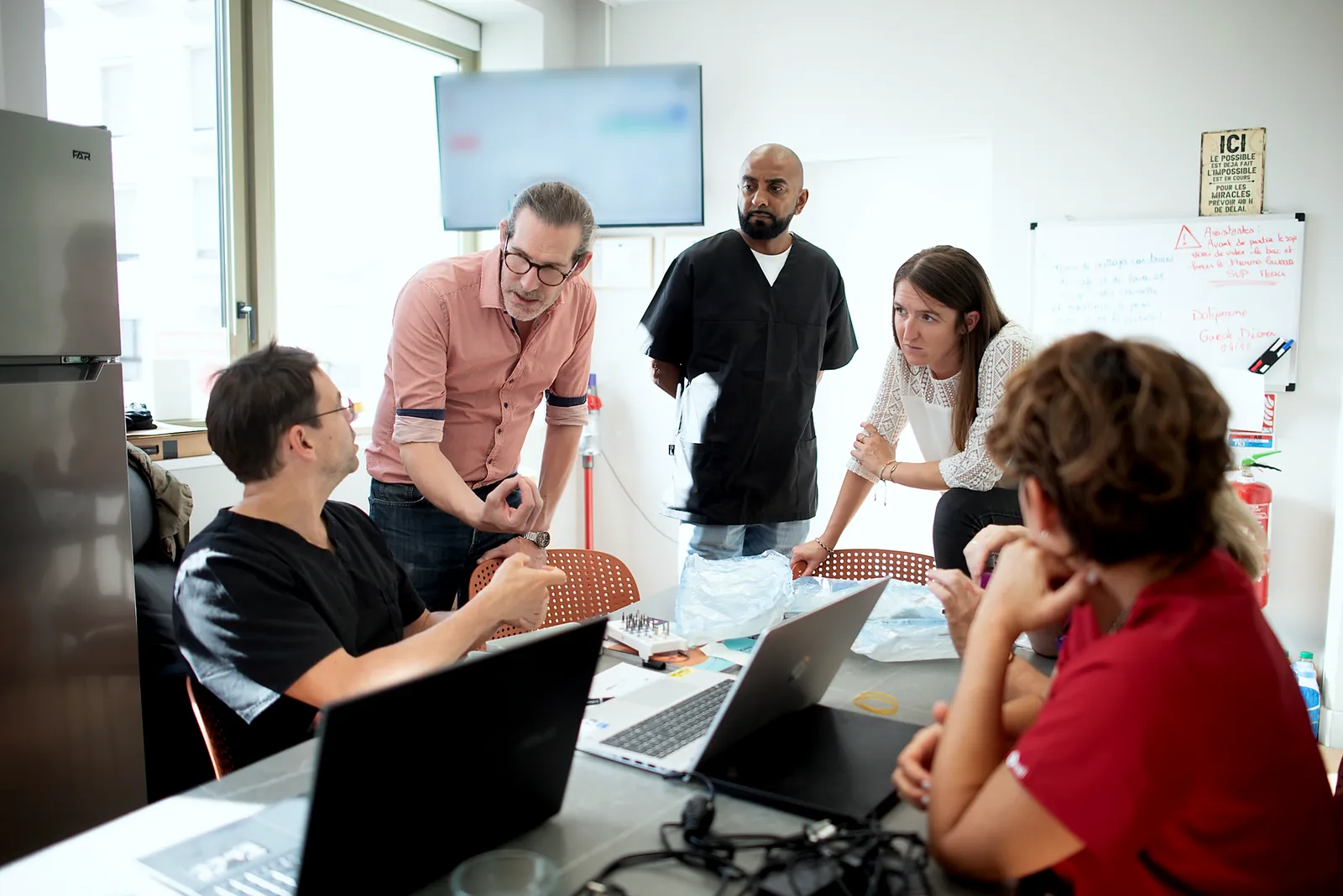 Session de formation : le formateur debout, les praticiens autour de la table